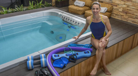 Une femme est assise à côté d'un spa de nage. De nombreux accessoires pour spa de nage sont placés à côté d'elle.