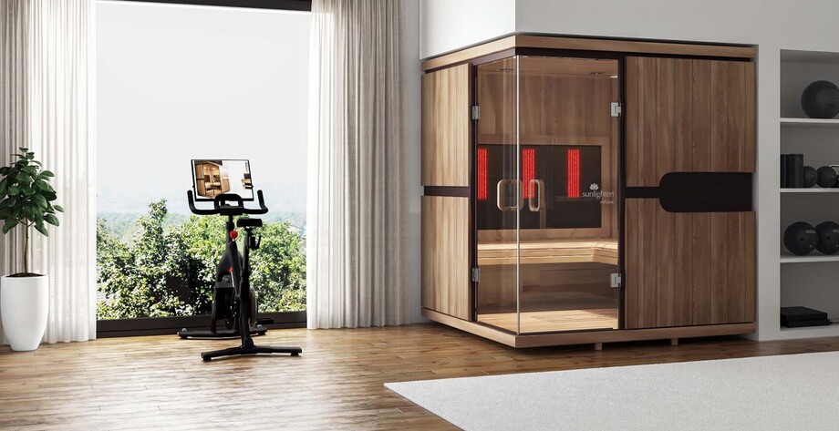 Un sauna infrarouge est installé dans une pièce, près d'un vélo d'appartement et d'accessoires de sport. 