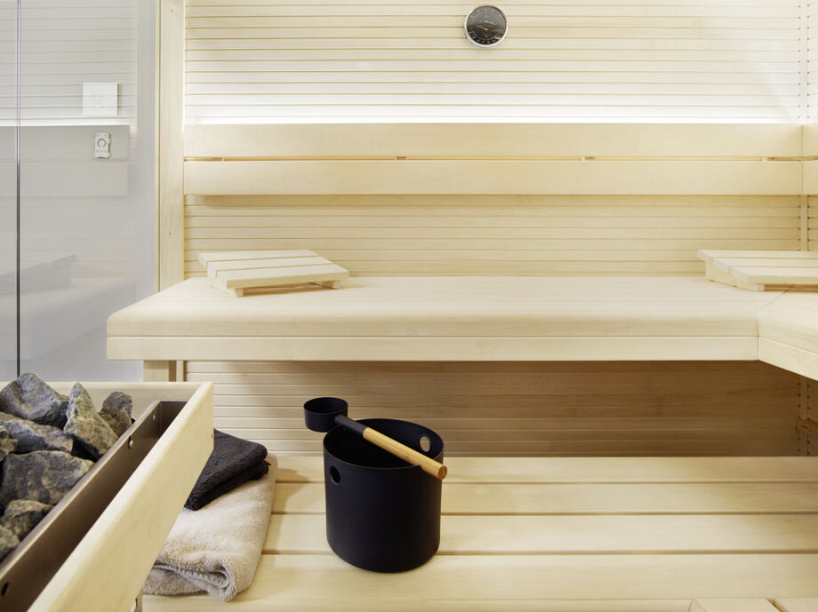 Zoom sur l'intérieur d'un sauna qui comporte des accessoires (seau, louche, etc.)
