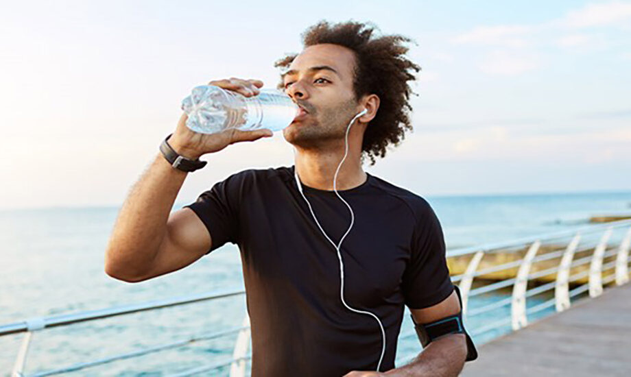 Un homme, lors d'une séance de sport, boit de l'eau. L'hydratation et l'activité physique font partie des façons de diminuer l'inflammation dans le corps naturellement.