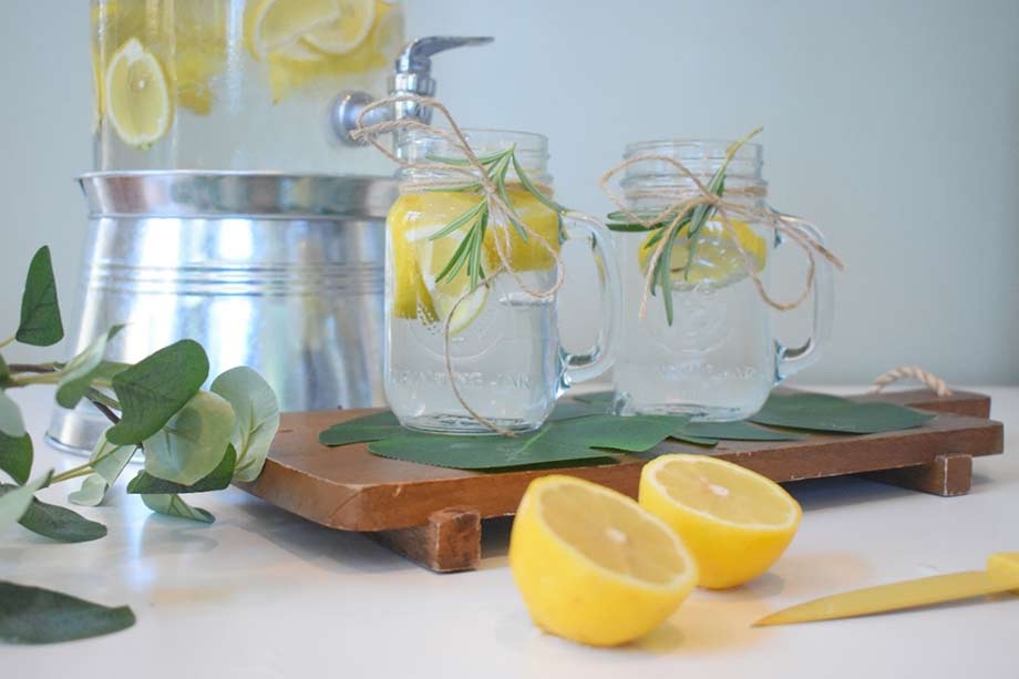Deux verres d'eau avec une tranche de citron sont posés sur une planche en bois. Une bonne hydratation permet de diminuer l'inflammation dans le corps. 