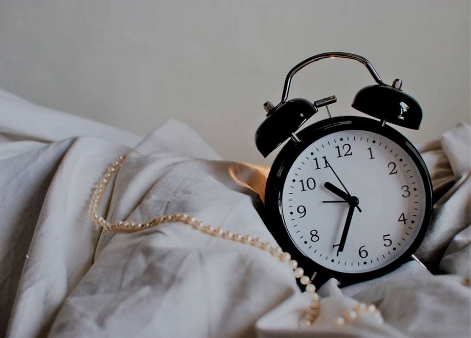 Un réveil est posé sur des draps. Dormir plus de 6 heures par nuit permettrait de diminuer l'inflammation dans le corps. 