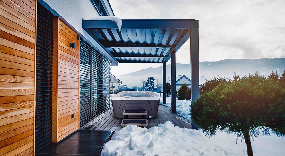 Hivernage spa: un bain à remous portable est placé sous une pergola bioclimatique qui le protège de la neige.