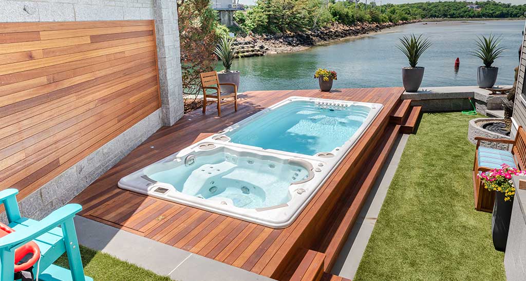 Spa de nage sur encastré dans une terrasse en bois au bord de l'eau