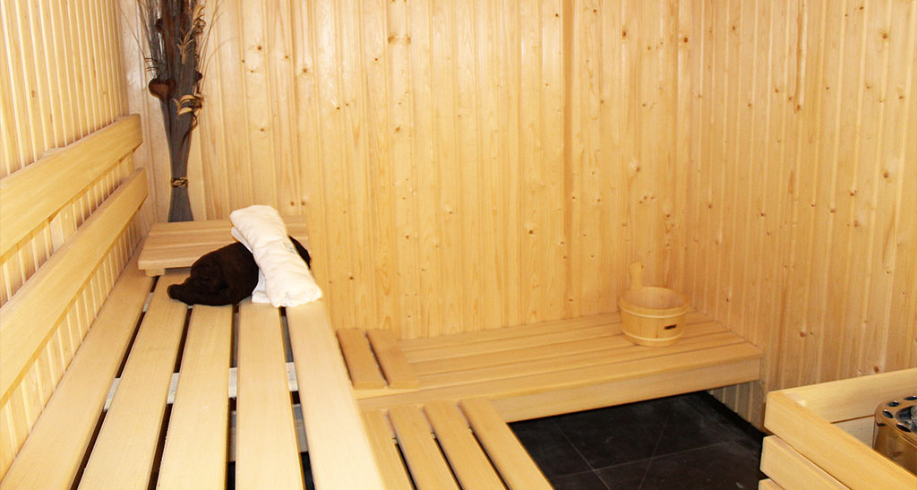 Sauna Lambris Sensation vu de l'intérieur avec un seau deux serviettes et une plate en arrière plan.