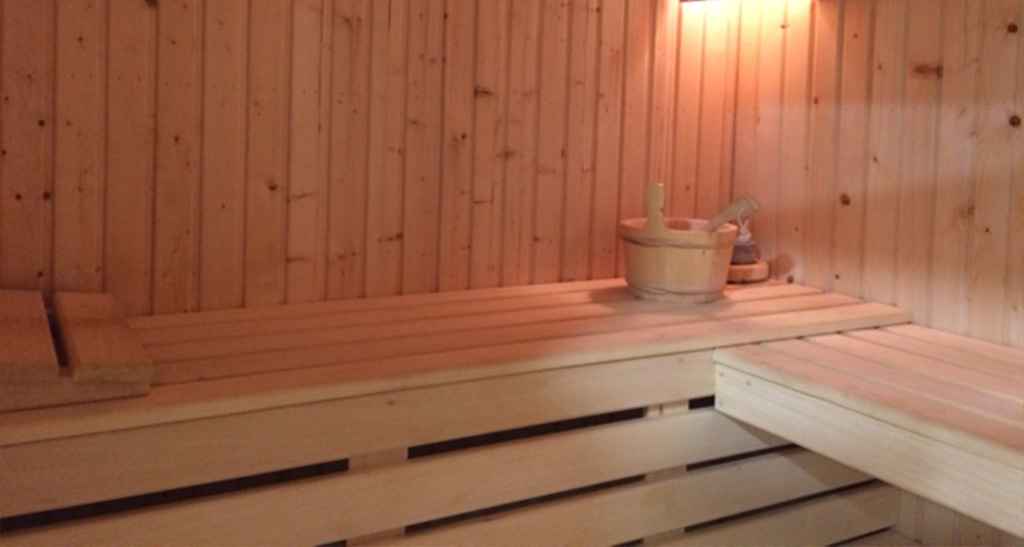 Zoom sur l'intérieur d'un sauna Lambris Sensation avec un seau en dessous d'une lumière d'ambiance.