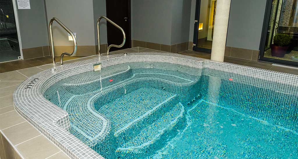 Spa de nage mosaïque Béatitude 700 encastré dans un centre de bien-être.