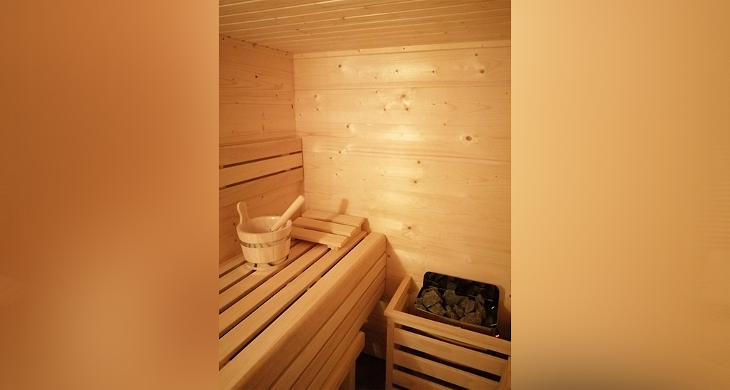 Zoom sur le coin d'un chalet sauna extérieur avec un seau et un four.