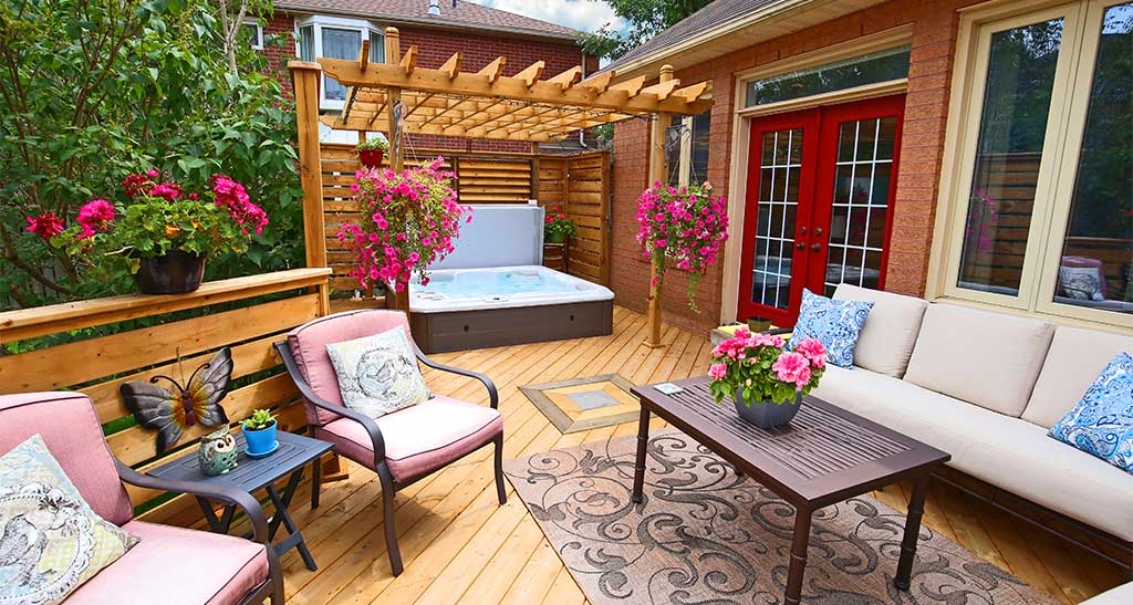 Terrasse aménagée avec un salon de jardin et un spa H670 sous une pergola en bois au fond.