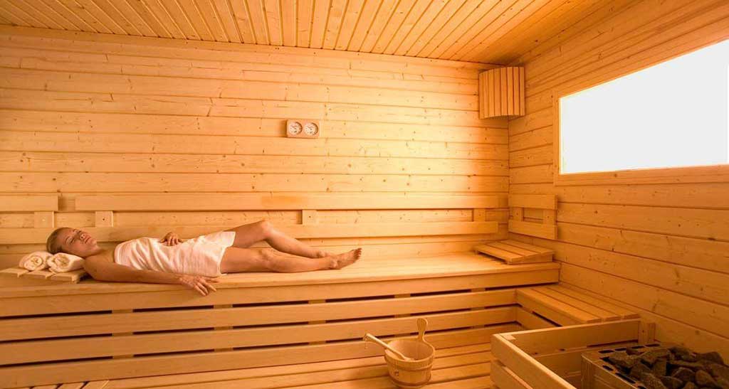 Femme en serviette allongée dans un sauna Massif Prestige.