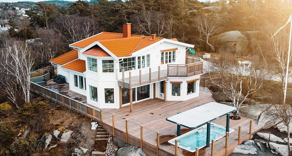 Image prise d'en haut vue sur la maison est le spa de nage 17AX encastré dans la terrasse en bois.