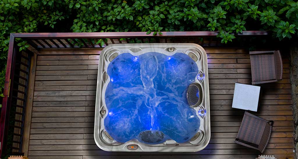 Un spa est installé sur une terrasse. Son eau est éclairée par des lumières.