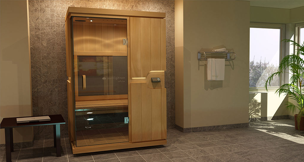 Cabine sauna Infrarouge Duo avec porte vitrée dans une pièce avec un sèche serviettes et une table avec un ordinateur sur le côté.