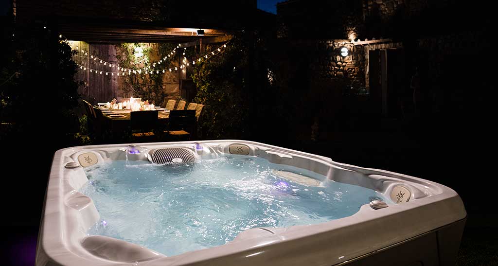 Un spa posé sur une terrasse dans la nuit.