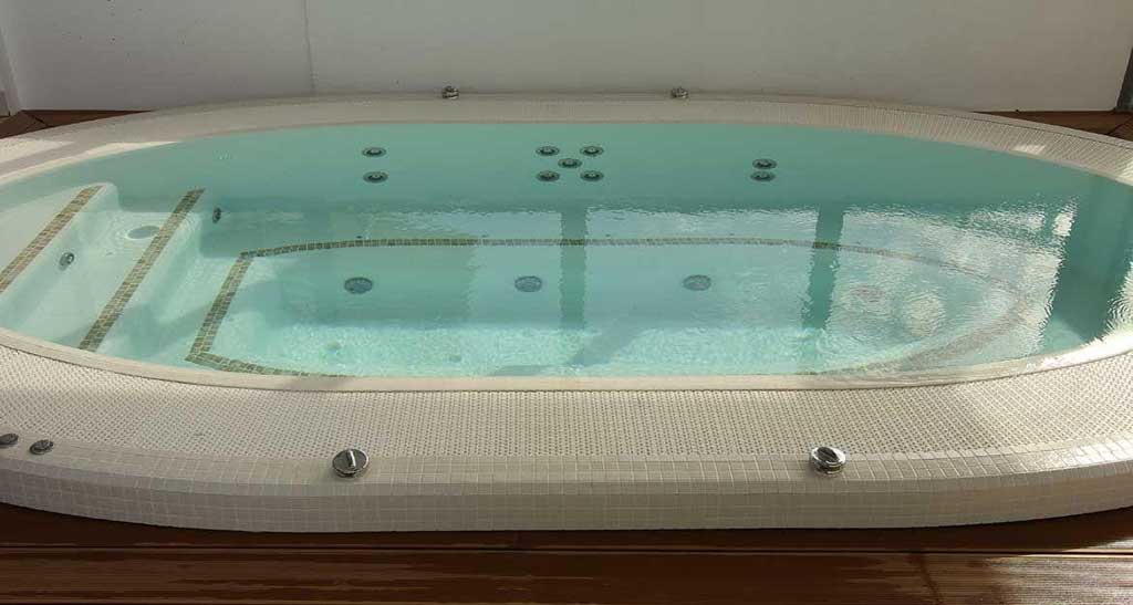 Zoom sur un spa à débordement Mosaic 360 blanc avec des détails marronés.