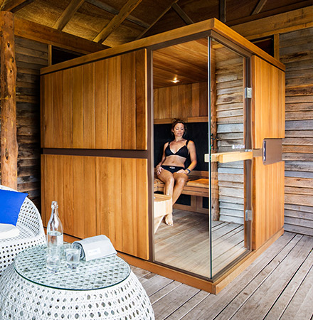 sauna infrarouge installé dans un angle d'une pièce avec une femme à l'intérieur