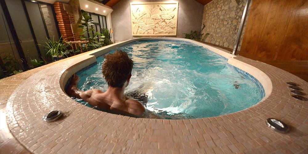 Un homme de dos installé dans un spa de nage en mosaïques
