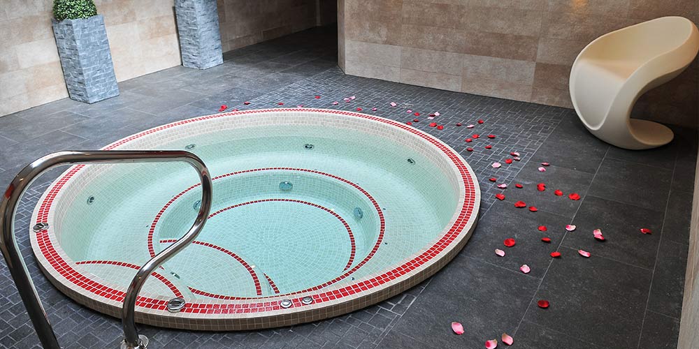 Spa mosaïque encastré en intérieur avec des pétales de roses tout autour