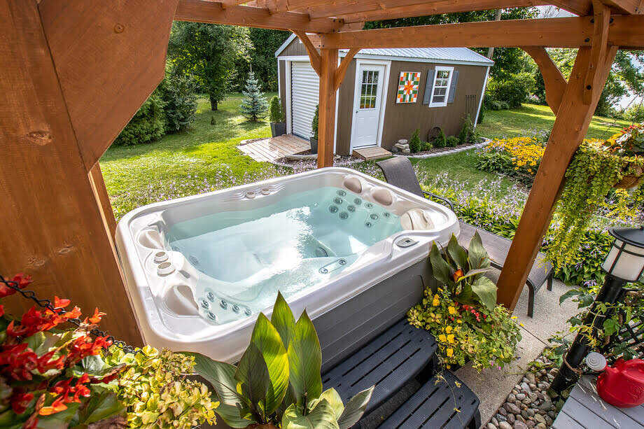 Un spa est installé dans un jardin. Il est entouré de plantes. 