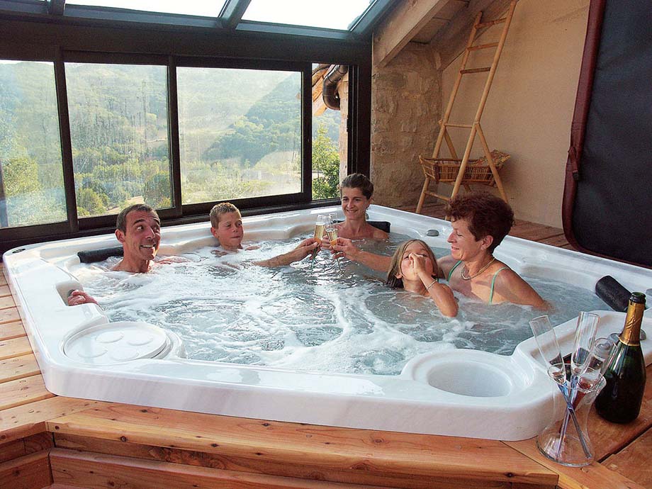 Une famille, confortablement installée dans un spa intérieur, partage un moment de convivialité autour d'une coupe de champagne. 