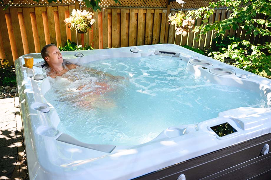 Un homme se prélasse dans un spa installé en extérieur et profite des jets de massage.