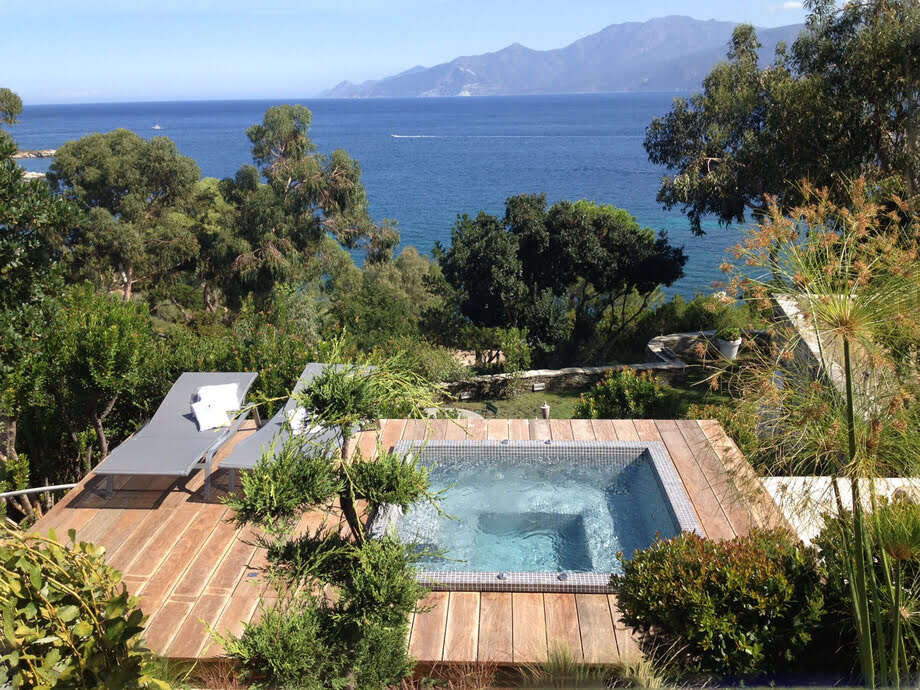 Un spa recouvert de mosaïque est encastré dans une terrasse qui offre une très belle vue sur la mer. 