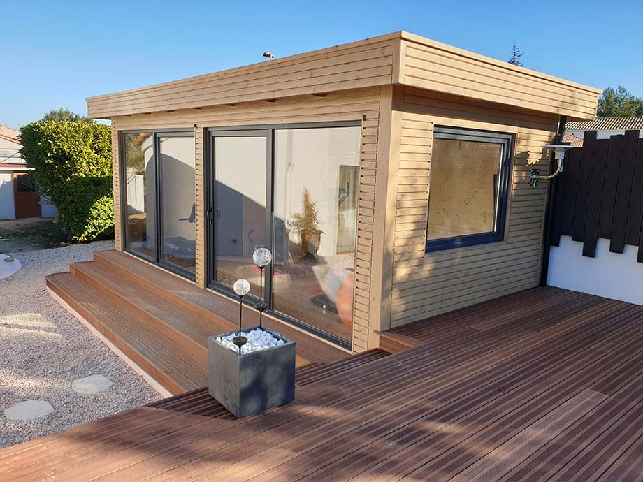 Un poolhouse est installé sur une terrasse en bois. 