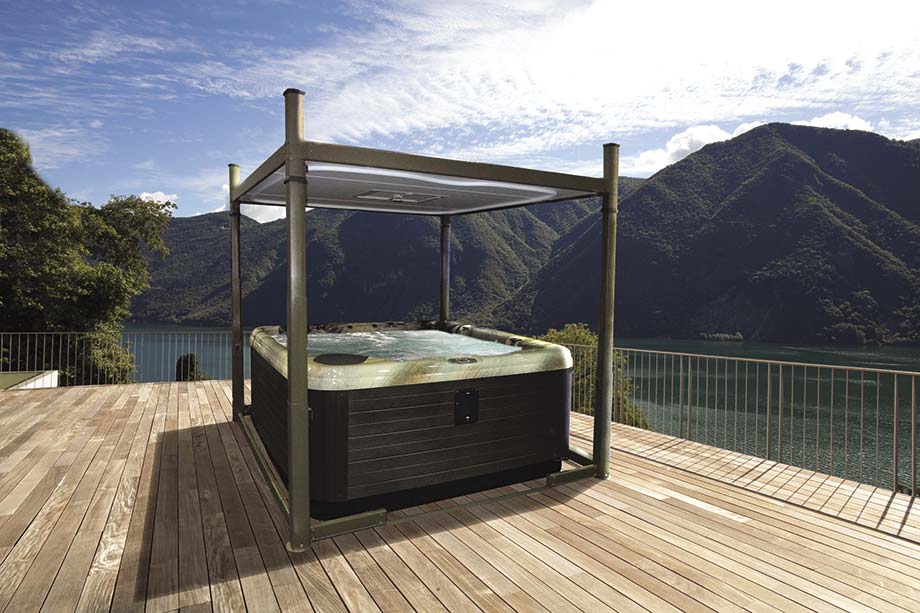 Un gazebo télescopique , sous lequel est placé un spa, est installé sur une terrasse en bois et offre une vue sur les montagnes. 