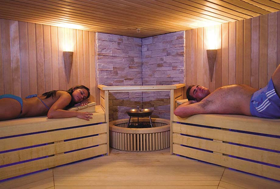 Un homme et une femme sont allongés sur les banquettes d'un sauna traditionnel. 