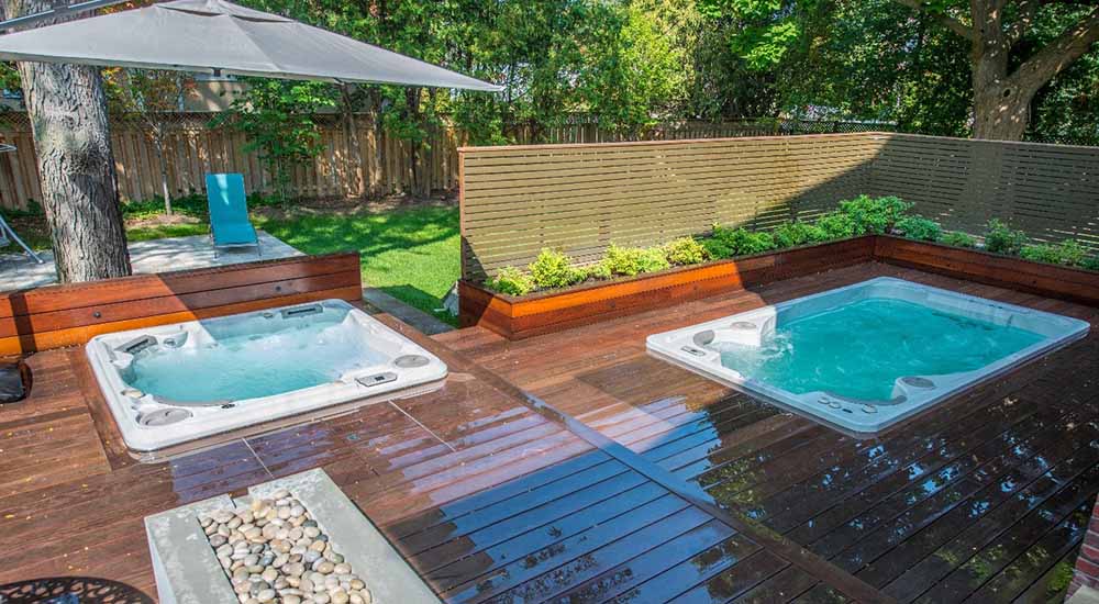 Un spa et un spa de nage sont installés à côté, sur une terrasse en bois. Les deux bassins sont encastrés.