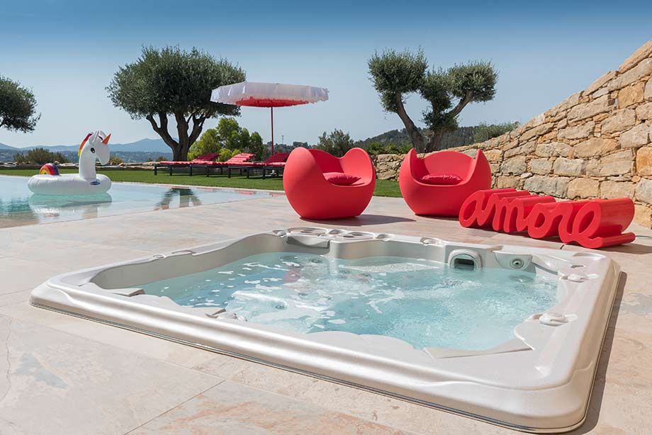 Un spa est installé à l'extérieur. Il est encastré dans une terrasse, à quelques pas d'une piscine. 