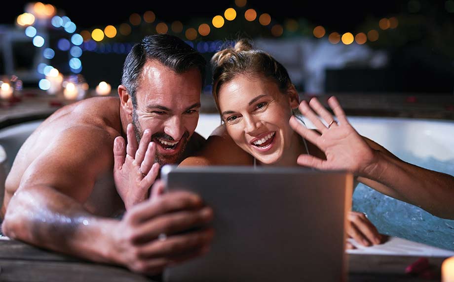 Un couple installé dans un spa utilise une tablette pour échanger avec leurs proches.