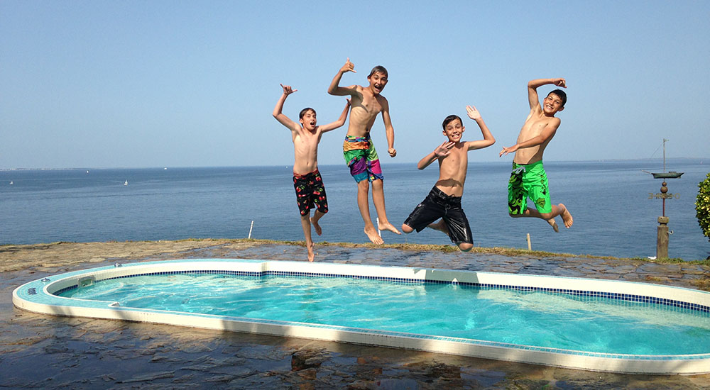 Quatre enfants sautent dans un spa de nage mosaïque.