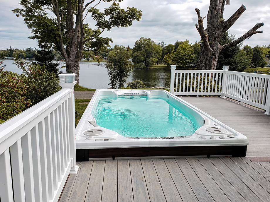 Un spa de nage est installé en extérieur et offre une vue sur un point d'eau. 