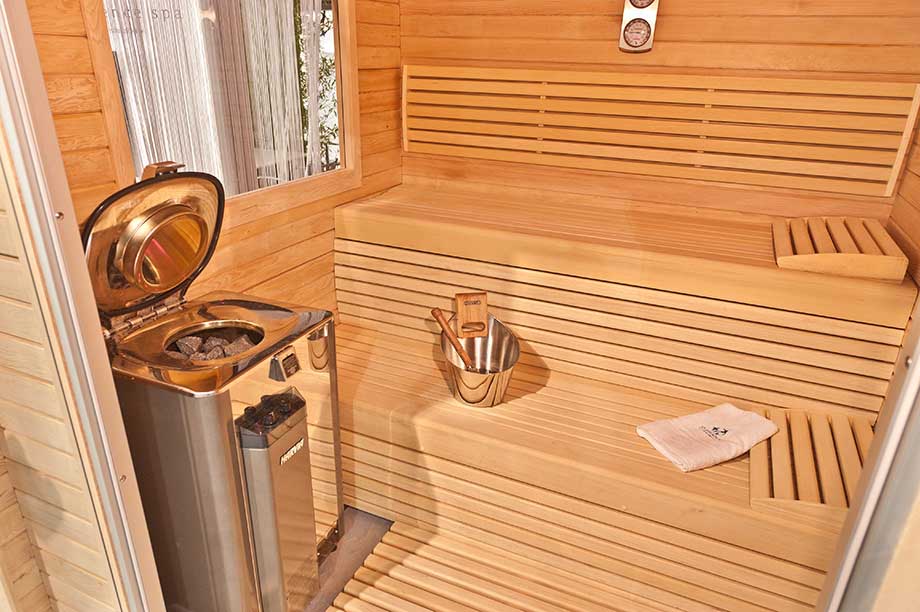 Zoom sur l'intérieur d'un sauna traditionnel en bois, équipé d'un poêle électrique. 