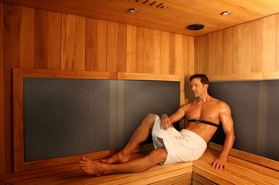 Un homme est allongée sur un banc d'un sauna infrarouge.