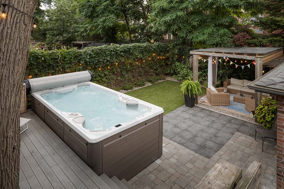Un grand spa portable est installé sur une terrasse, à proximité d'un salon de jardin. 