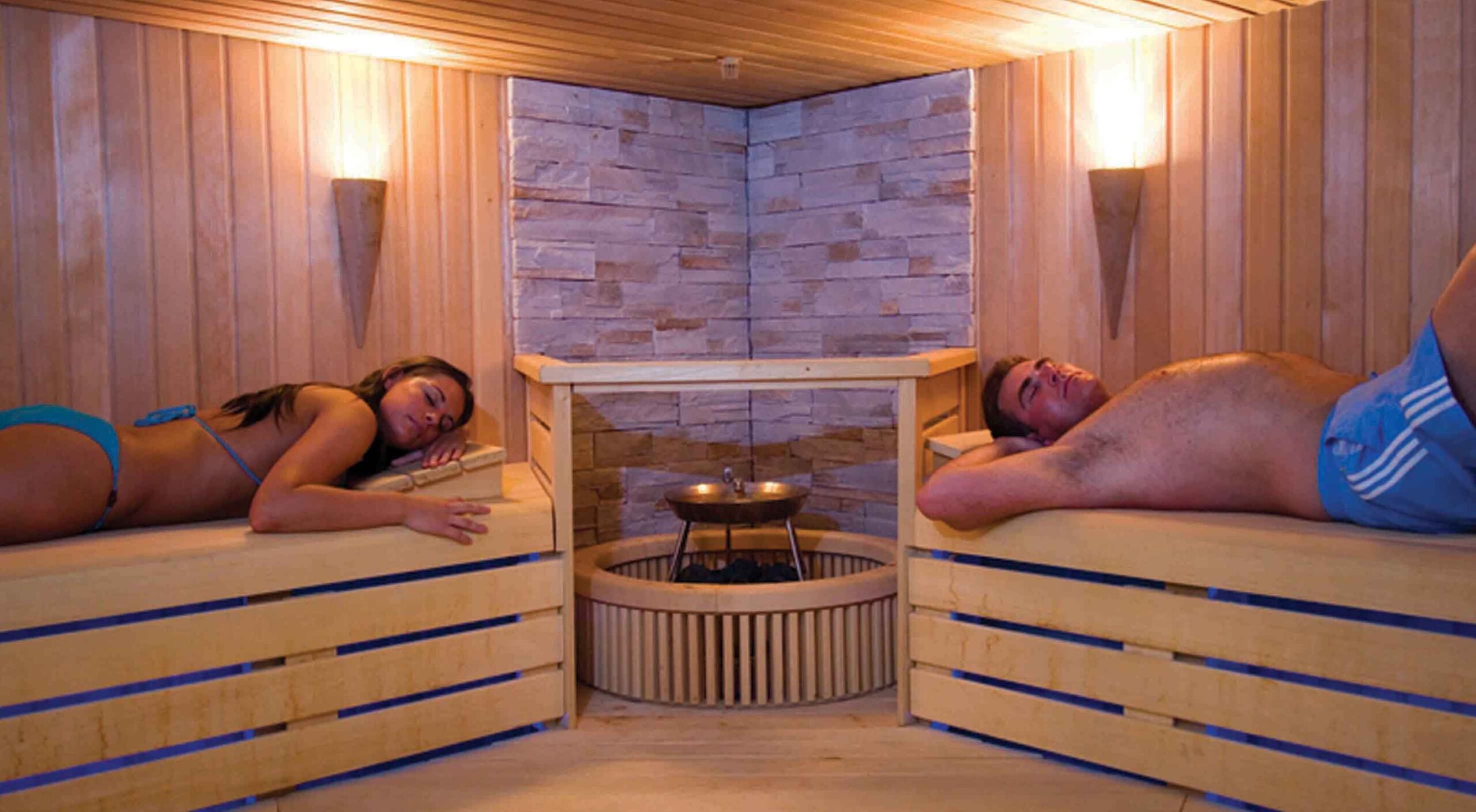 Deux personnes sont allongées dans un sauna équipé d'un poêle électrique.
