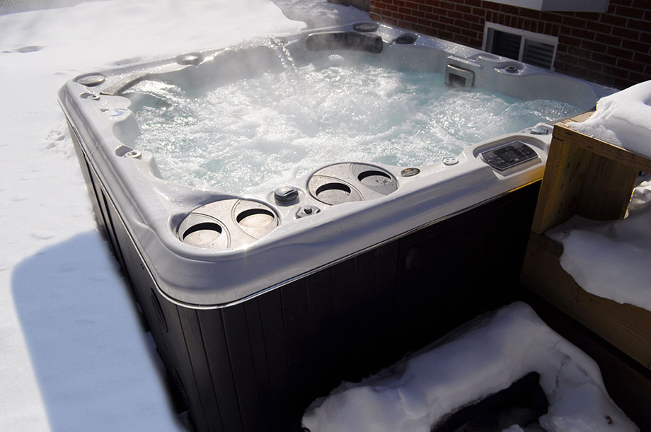 Hivernage spa : un spa portable est installé en extérieur. Le sol est recouvert de neige. 