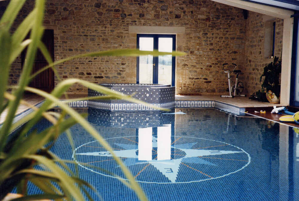 Un spa est installé contre une piscine intérieure. 