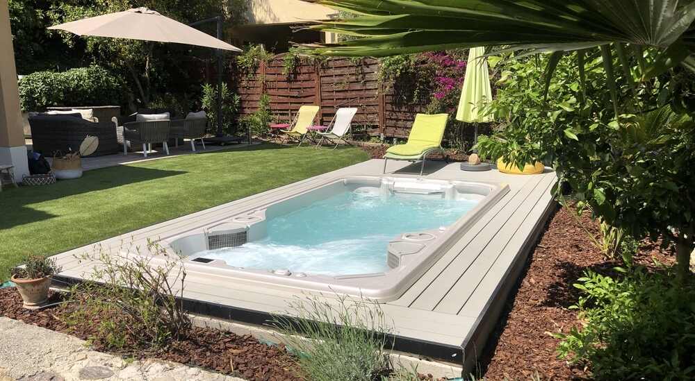 Jacuzzi® VS Clairazur Un spa de nage est installé dans un jardin.