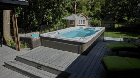 Quelle taille de spa de nage choisir ? Sur cette photo, un spa de nage est installé sur une terrasse, dans un jardin.