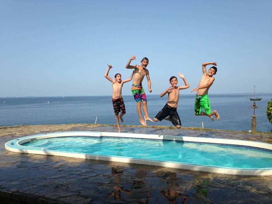 Quatre enfants sautent dans un spa de nage en mosaïque. 