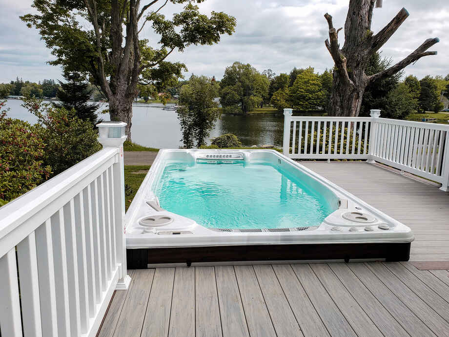 Un spa de nage est installé sur une terrasse et bénéficie d'une jolie vue. 