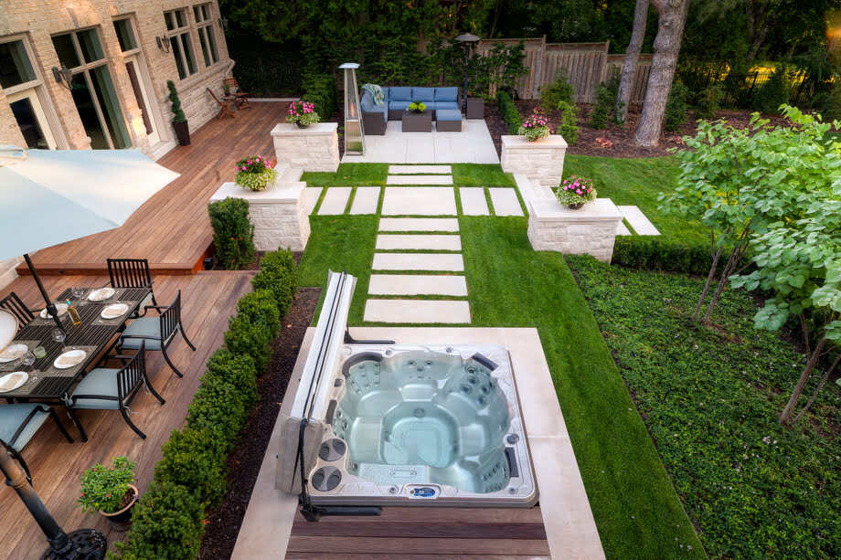 Un spa est installé en extérieur, dans un jardin près d'une terrasse. 