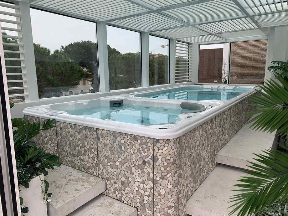 Un spa de nage bi-zone est installé en intérieur, dans une véranda. 