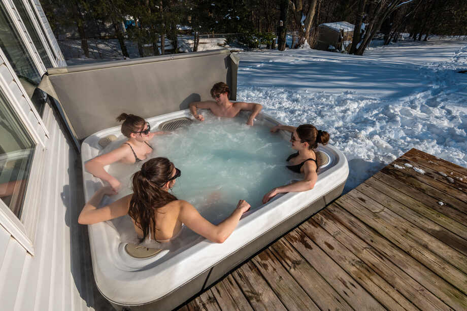 Quatre personnes se baignent dans un spa rigide, installé en extérieur. 