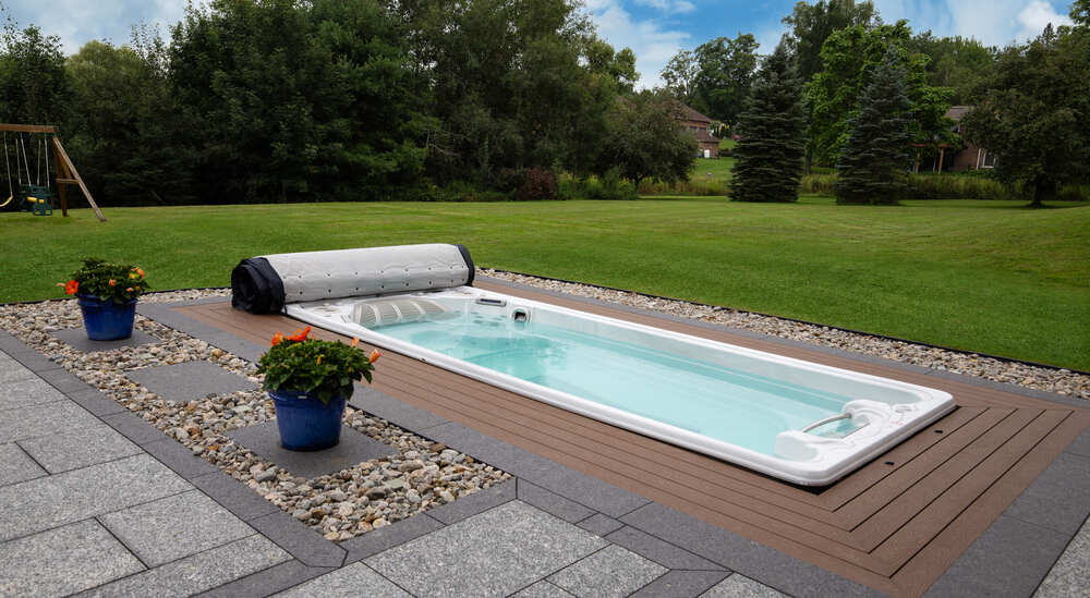 Un spa de nage est installé en extérieur, dans un grand jardin.