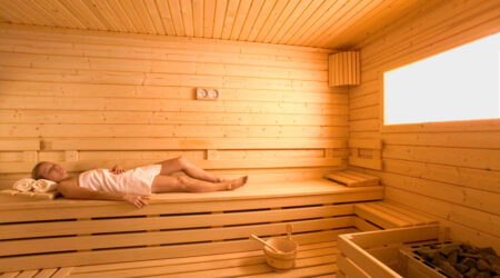 Quelle est la consommation électrique d'un sauna ? Une femme est allongée dans un sauna traditionnel.