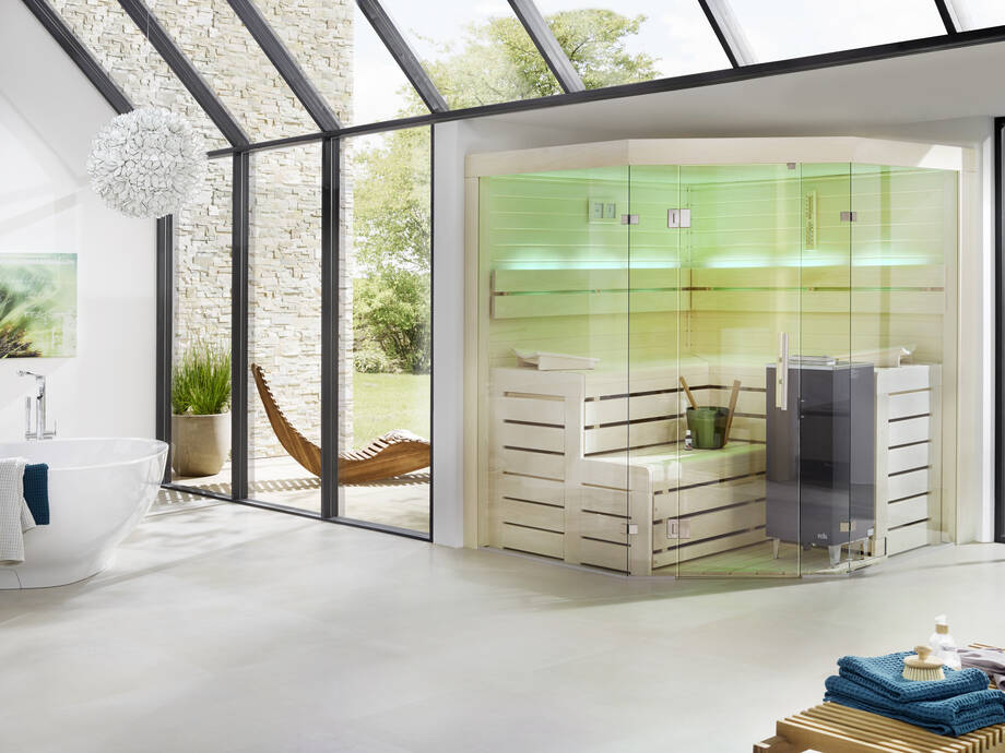 Un sauna est installé dans une pièce lumineuse, à proximité d'une baignoire. 